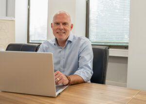 rob smiling to camera with laptop