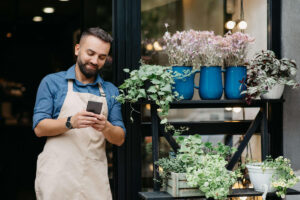 Man in apron texting outside cafe