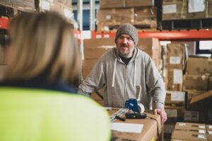 Male Warehouse Worker In Wooly Hat In Warehouse